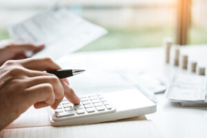 Man using calculator accounting calculating cost economic bills with money stack step growing growth saving money in home , finance concept